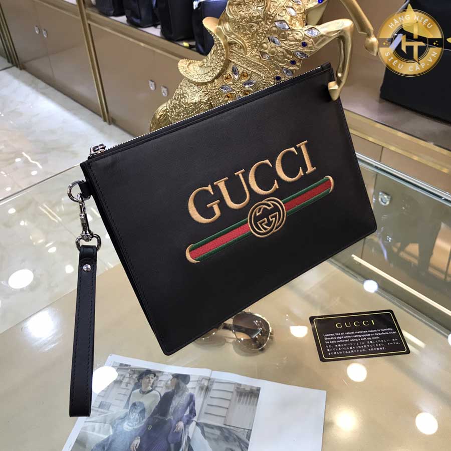 Chữ Gucci màu vàng được in nổi bật trên nền màu đen của clutch cầm tay hàng hiệu Gucci